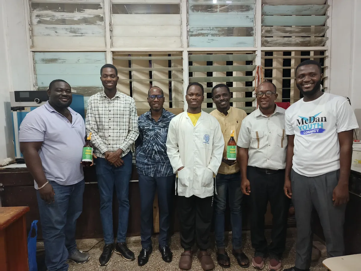 Seven people smiling in the Forefront Innovations laboratory, two of them holding FreshGuard bottles